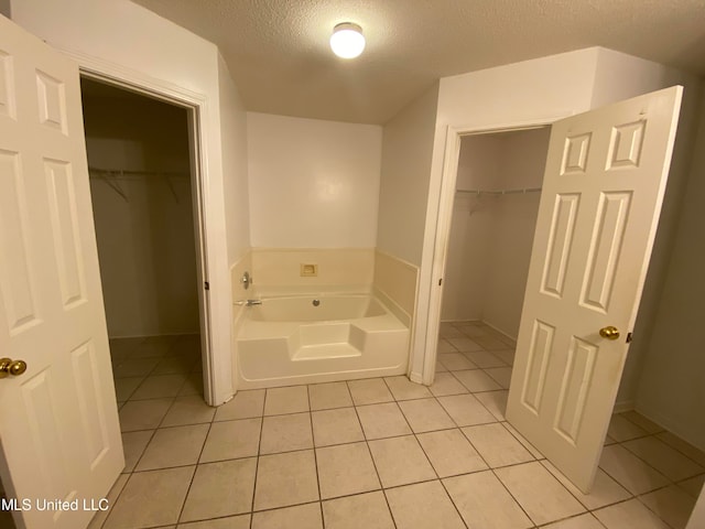 bathroom featuring tile patterned floors, a textured ceiling, and a bath