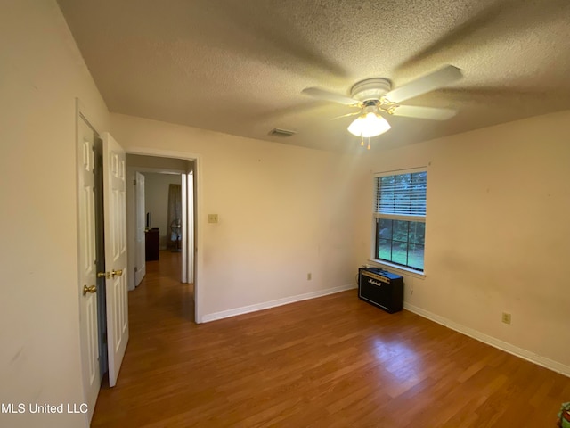 spare room with ceiling fan, wood-type flooring, and a textured ceiling