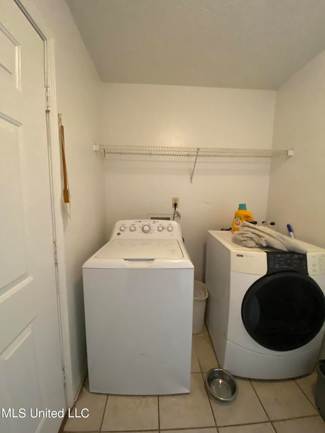 laundry area with light tile patterned flooring and washer and clothes dryer