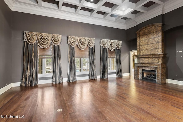 unfurnished living room featuring hardwood / wood-style flooring, coffered ceiling, a towering ceiling, and beam ceiling