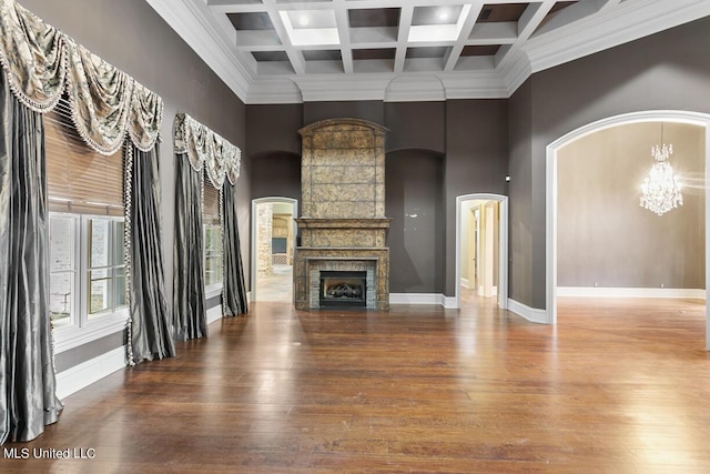 unfurnished living room with a high ceiling, hardwood / wood-style flooring, a chandelier, and beam ceiling