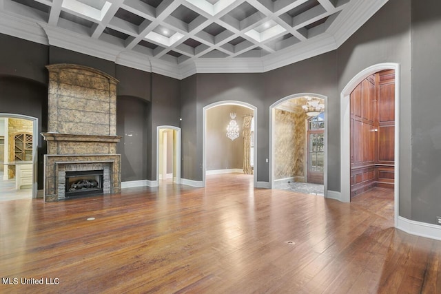 unfurnished living room featuring beam ceiling, a towering ceiling, wood-type flooring, and coffered ceiling