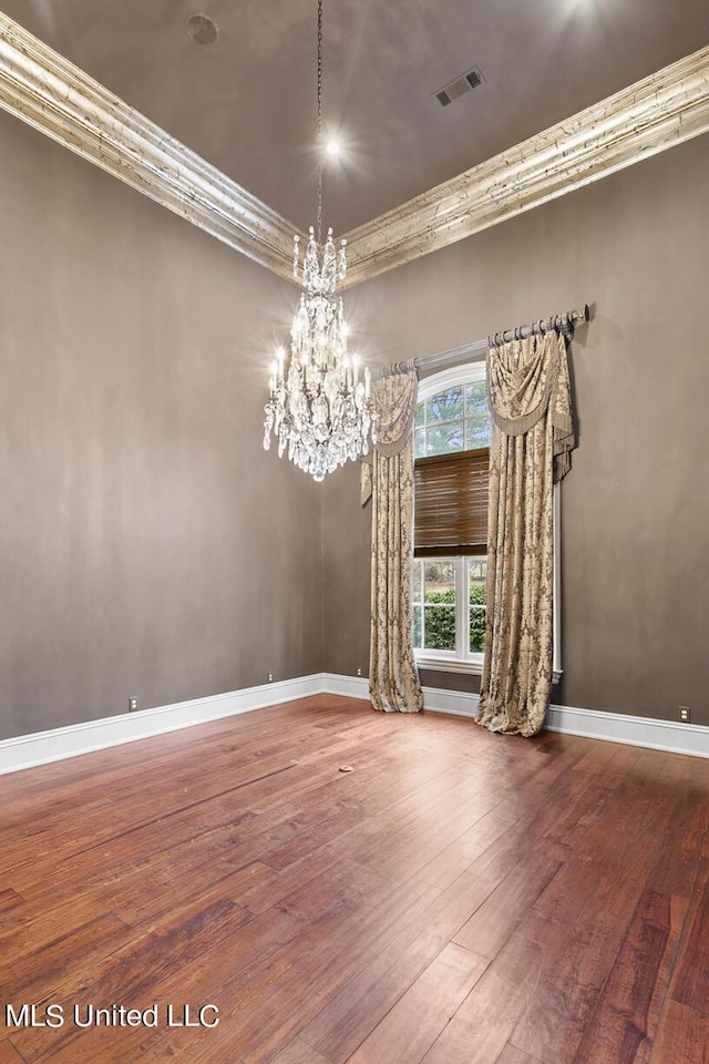 spare room featuring ornamental molding, hardwood / wood-style floors, and a chandelier