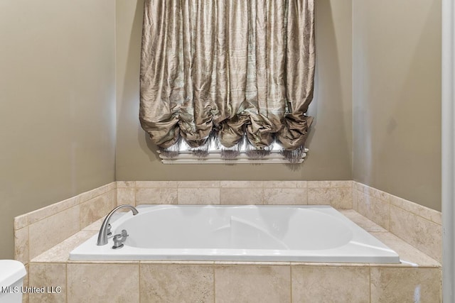 bathroom featuring tiled tub and toilet