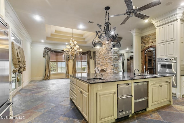 kitchen featuring hanging light fixtures, a tray ceiling, sink, and cream cabinetry