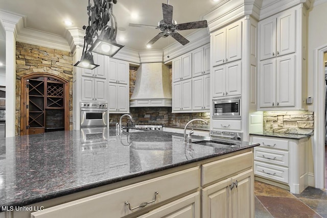 kitchen with sink, dark stone countertops, appliances with stainless steel finishes, custom range hood, and white cabinets