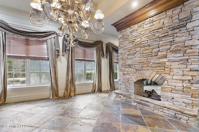 unfurnished living room with crown molding, a stone fireplace, and an inviting chandelier