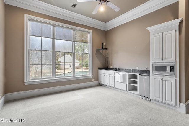 interior space with stainless steel microwave, refrigerator, white cabinetry, ornamental molding, and light carpet