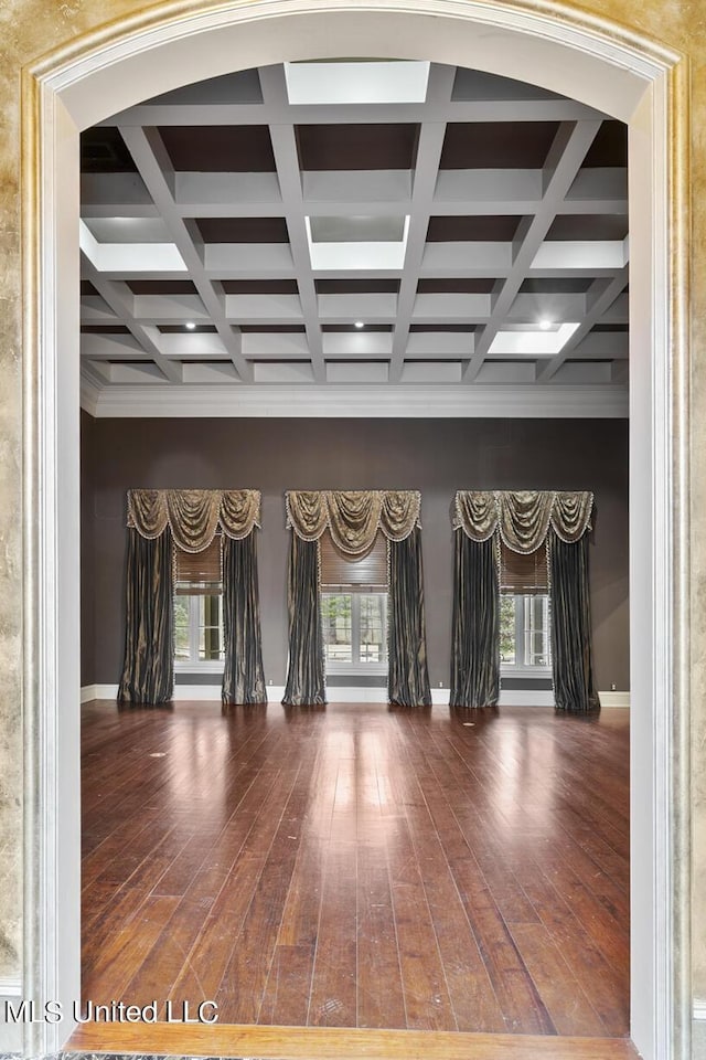 unfurnished room featuring coffered ceiling, dark wood-type flooring, and beam ceiling