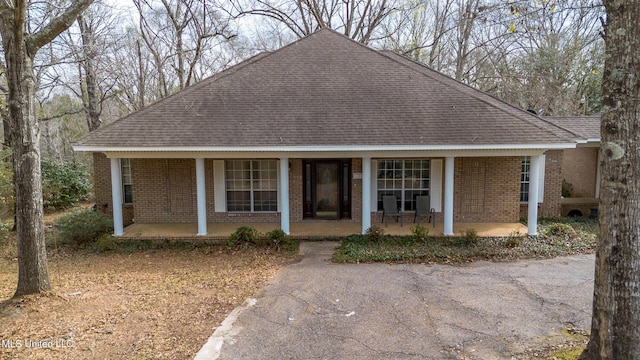 view of front of house featuring a porch, brick siding, and a shingled roof