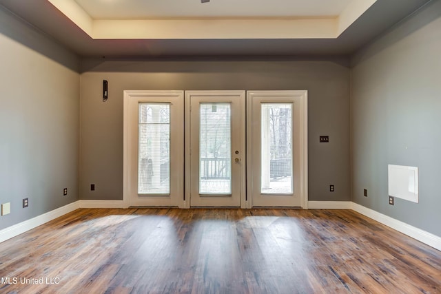 doorway featuring baseboards, a raised ceiling, and wood finished floors