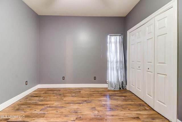 unfurnished bedroom featuring a closet, wood finished floors, and baseboards