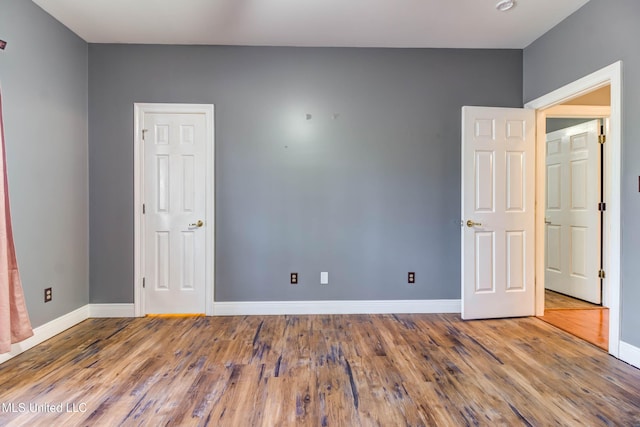 spare room with baseboards and wood finished floors