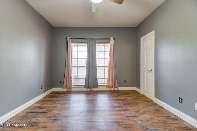 empty room with ceiling fan, wood finished floors, and baseboards