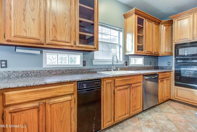 kitchen featuring black appliances, brown cabinetry, a sink, and glass insert cabinets