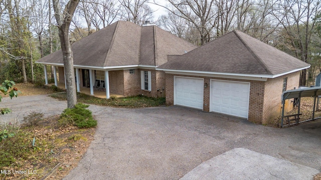 view of front of house with a garage, brick siding, driveway, and roof with shingles