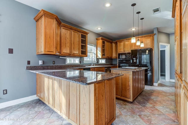 kitchen with visible vents, brown cabinetry, dark stone countertops, a peninsula, and black appliances