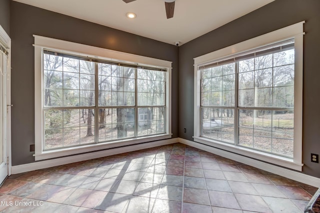 interior space featuring a ceiling fan, baseboards, and a wealth of natural light