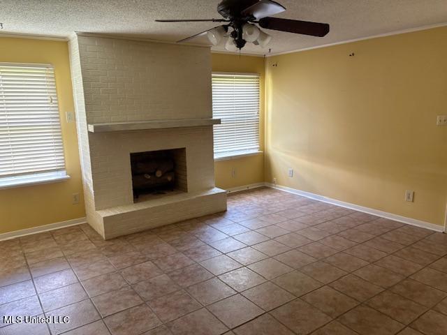3 Pemberton Cir, Greenwood, MS 38930 - unfurnished living room featuring ceiling fan, ornamental molding, a textured ceiling, tile patterned floors, and a brick fireplace