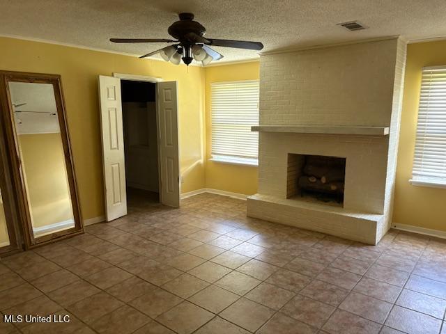 3 Pemberton Cir, Greenwood, MS 38930 - unfurnished living room with a textured ceiling, a ceiling fan, crown molding, tile patterned floors, and a fireplace