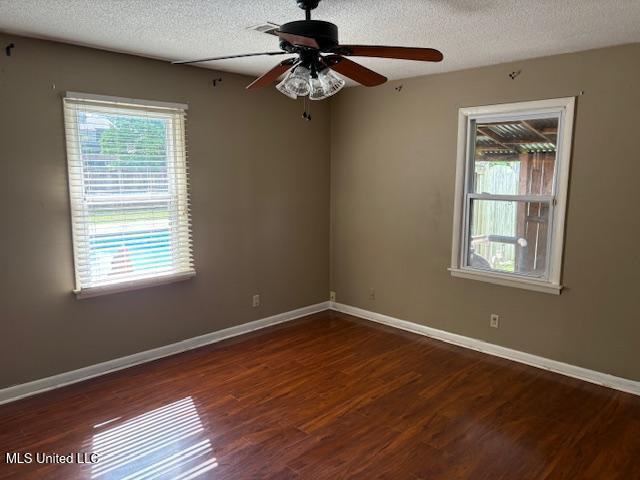 3 Pemberton Cir, Greenwood, MS 38930 - empty room with plenty of natural light, wood finished floors, a ceiling fan, baseboards, and a textured ceiling