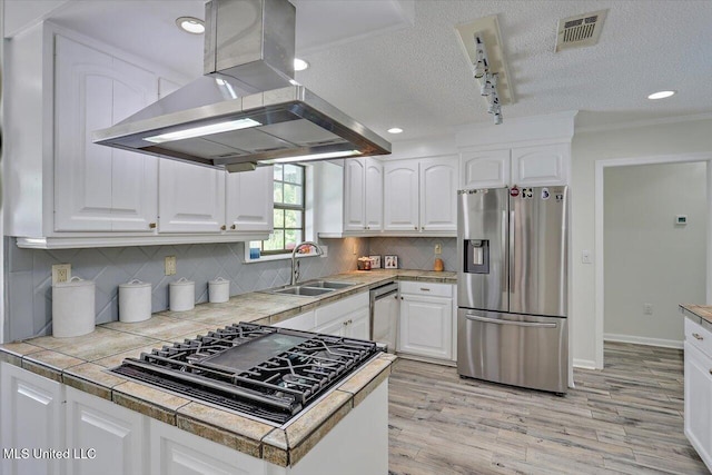 110 Stonington Ct, Brandon, MS 39047 - kitchen featuring appliances with stainless steel finishes, island range hood, white cabinets, a textured ceiling, and light wood-style floors