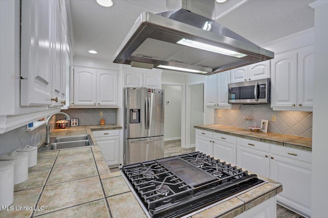 110 Stonington Ct, Brandon, MS 39047 - kitchen with stainless steel appliances, wall chimney exhaust hood, white cabinets, decorative backsplash, and tile countertops