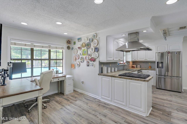 110 Stonington Ct, Brandon, MS 39047 - kitchen featuring stainless steel appliances, wall chimney range hood, white cabinetry, light wood-type flooring, and a textured ceiling