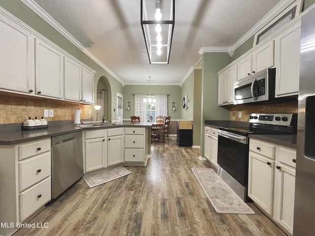 5269 Blocker St, Olive Branch, MS 38654 - kitchen with stainless steel appliances, a peninsula, dark wood finished floors, dark countertops, and tasteful backsplash