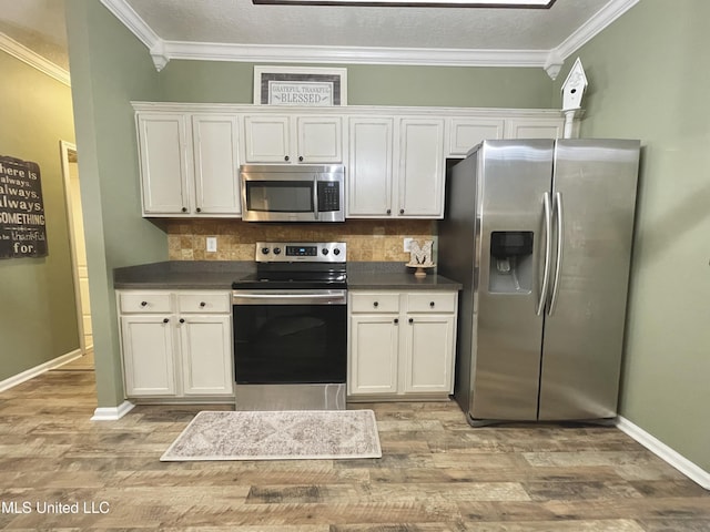 5269 Blocker St, Olive Branch, MS 38654 - kitchen featuring stainless steel appliances, dark countertops, light wood-style floors, decorative backsplash, and crown molding