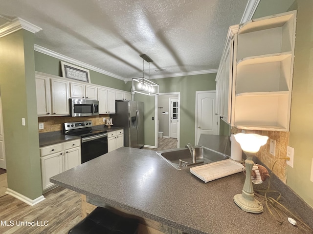 5269 Blocker St, Olive Branch, MS 38654 - kitchen featuring appliances with stainless steel finishes, dark countertops, a peninsula, ornamental molding, and white cabinets