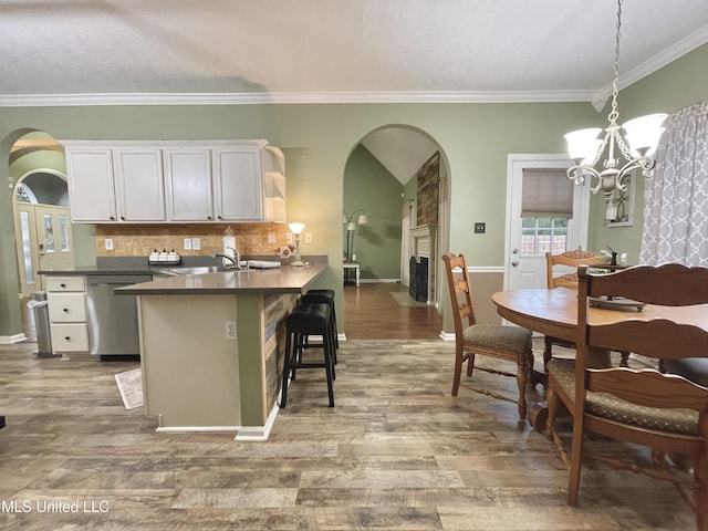 5269 Blocker St, Olive Branch, MS 38654 - kitchen featuring arched walkways, stainless steel dishwasher, dark countertops, a chandelier, and wood finished floors