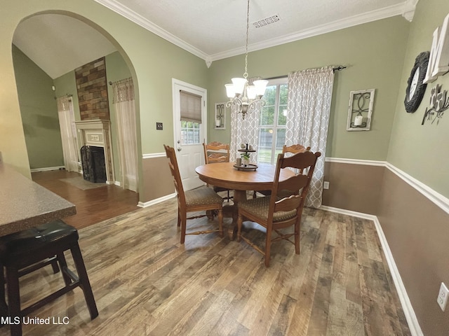 5269 Blocker St, Olive Branch, MS 38654 - dining area with wood finished floors, arched walkways, crown molding, a fireplace with flush hearth, and a chandelier