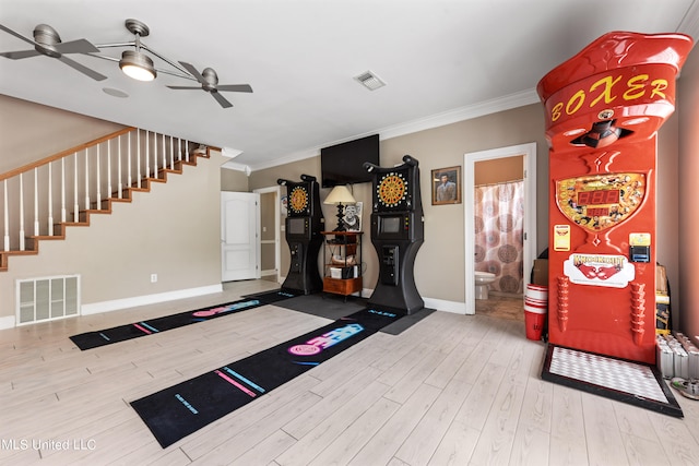 exercise area featuring crown molding, light wood-type flooring, and ceiling fan