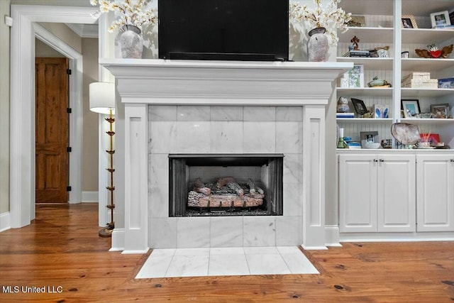 details with wood-type flooring, ornamental molding, and a tile fireplace