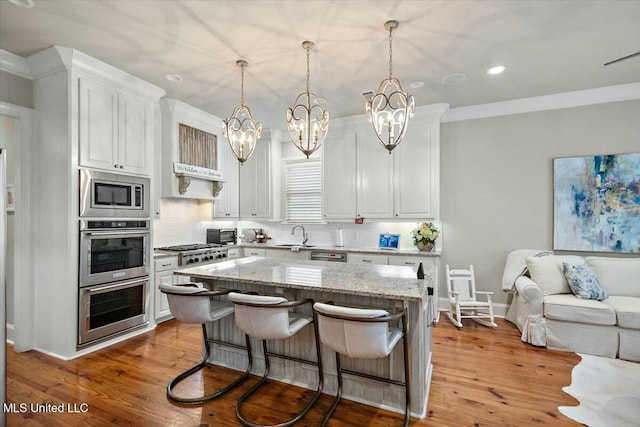 kitchen featuring white cabinetry, a center island, stainless steel appliances, pendant lighting, and a kitchen bar