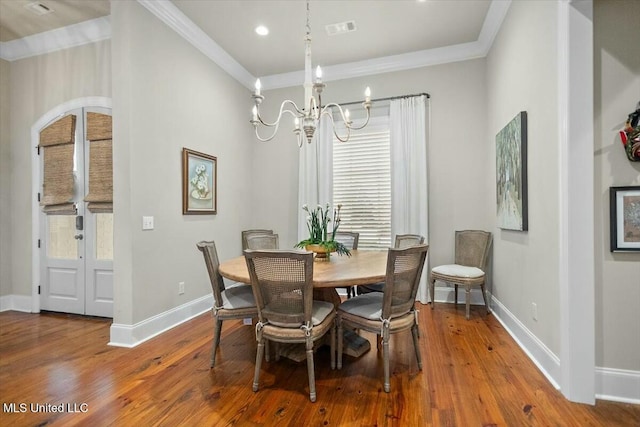 dining area with crown molding, hardwood / wood-style flooring, and an inviting chandelier