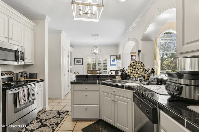 kitchen with stainless steel appliances, a peninsula, light tile patterned flooring, and white cabinets