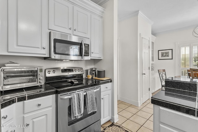 kitchen featuring light tile patterned floors, a toaster, stainless steel appliances, white cabinets, and dark countertops