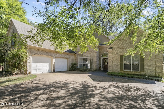 view of front of property with a garage, driveway, brick siding, and a shingled roof