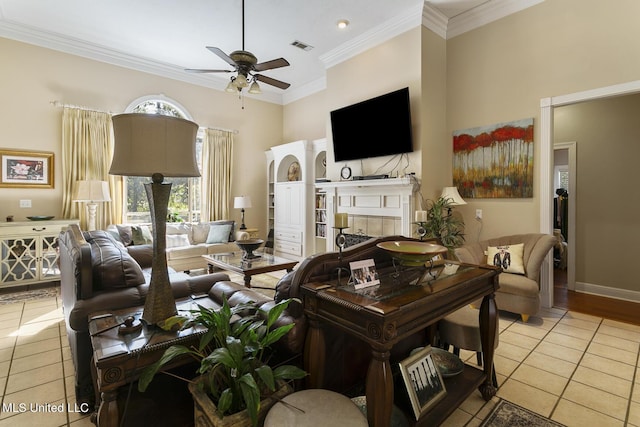 living room featuring a ceiling fan, a tile fireplace, light tile patterned flooring, and crown molding