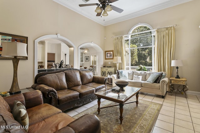 living area with arched walkways, ceiling fan, light tile patterned floors, a high ceiling, and ornamental molding