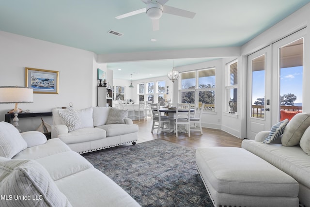 living room featuring ceiling fan with notable chandelier, wood finished floors, and visible vents