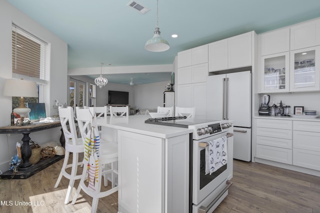 kitchen featuring white appliances, dark wood-style floors, visible vents, white cabinets, and pendant lighting