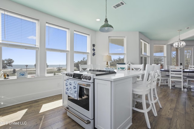 kitchen featuring visible vents, white range with electric stovetop, dark wood-style flooring, decorative light fixtures, and a center island