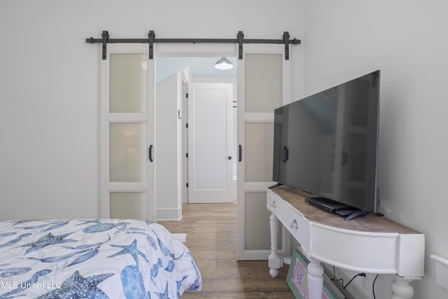 bedroom featuring a barn door and wood finished floors