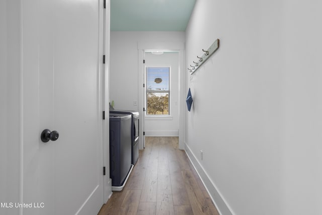 clothes washing area with washer and dryer, laundry area, baseboards, and hardwood / wood-style floors