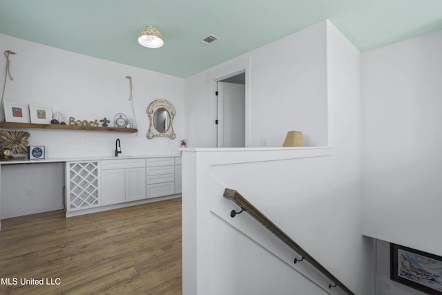 interior space with a sink, an upstairs landing, and wood finished floors