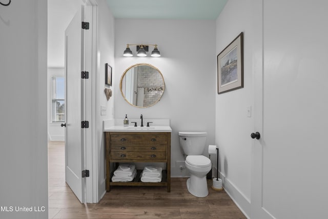 bathroom featuring toilet, vanity, baseboards, and wood finished floors