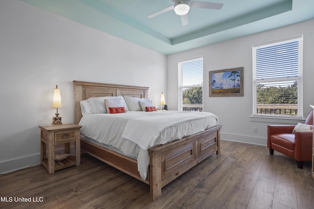 bedroom with baseboards, a ceiling fan, a tray ceiling, and hardwood / wood-style floors